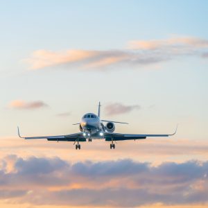 Private jet on the background of a beautiful gentle sky with clouds at sunset in pink and blue tones