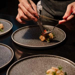 Close up of a chef’s hand cooking and preparing fine dining meals. Food prepping in the kitchen.