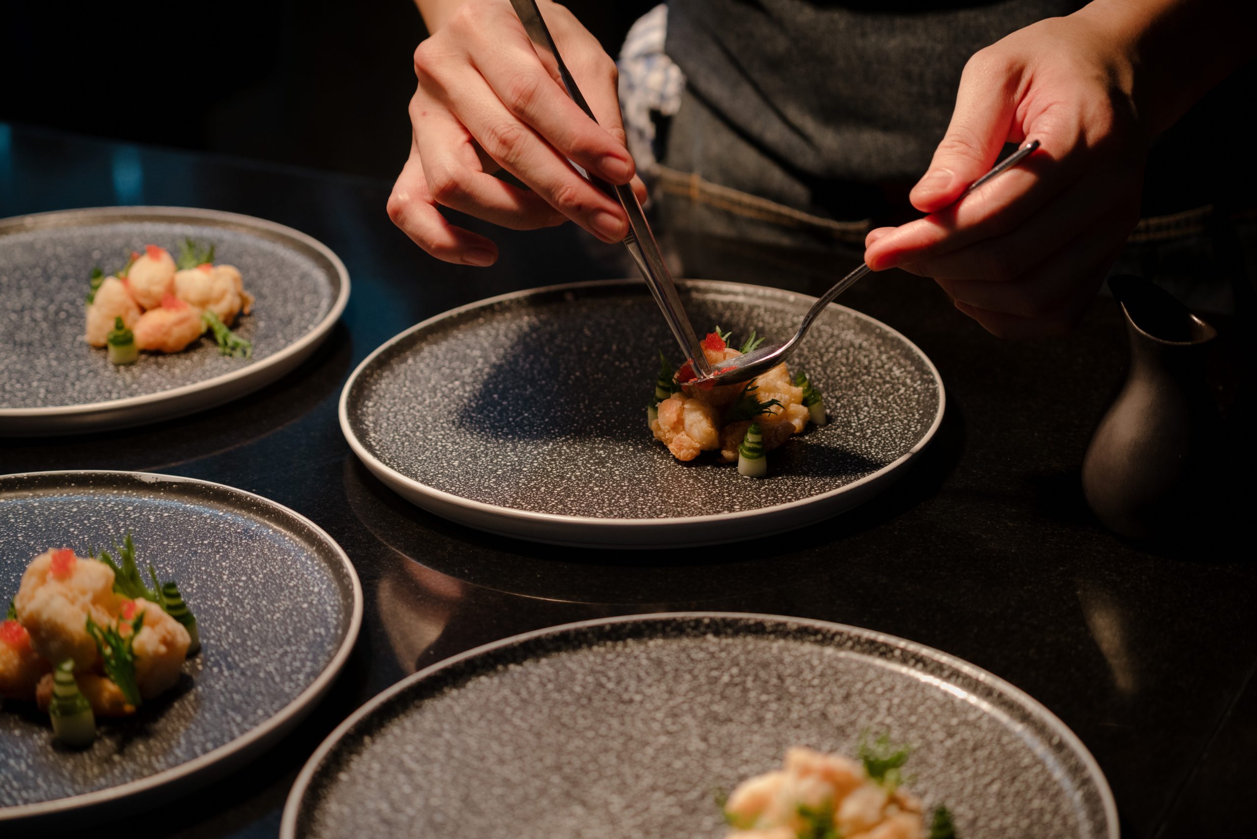 Close up of a chef's hand cooking and preparing fine dining meals. Food prepping in the kitchen.